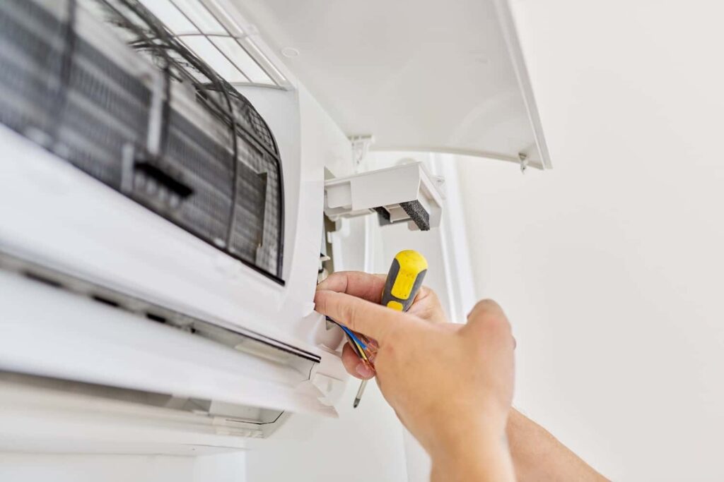 A technician repairing a wall air conditioner in Miami